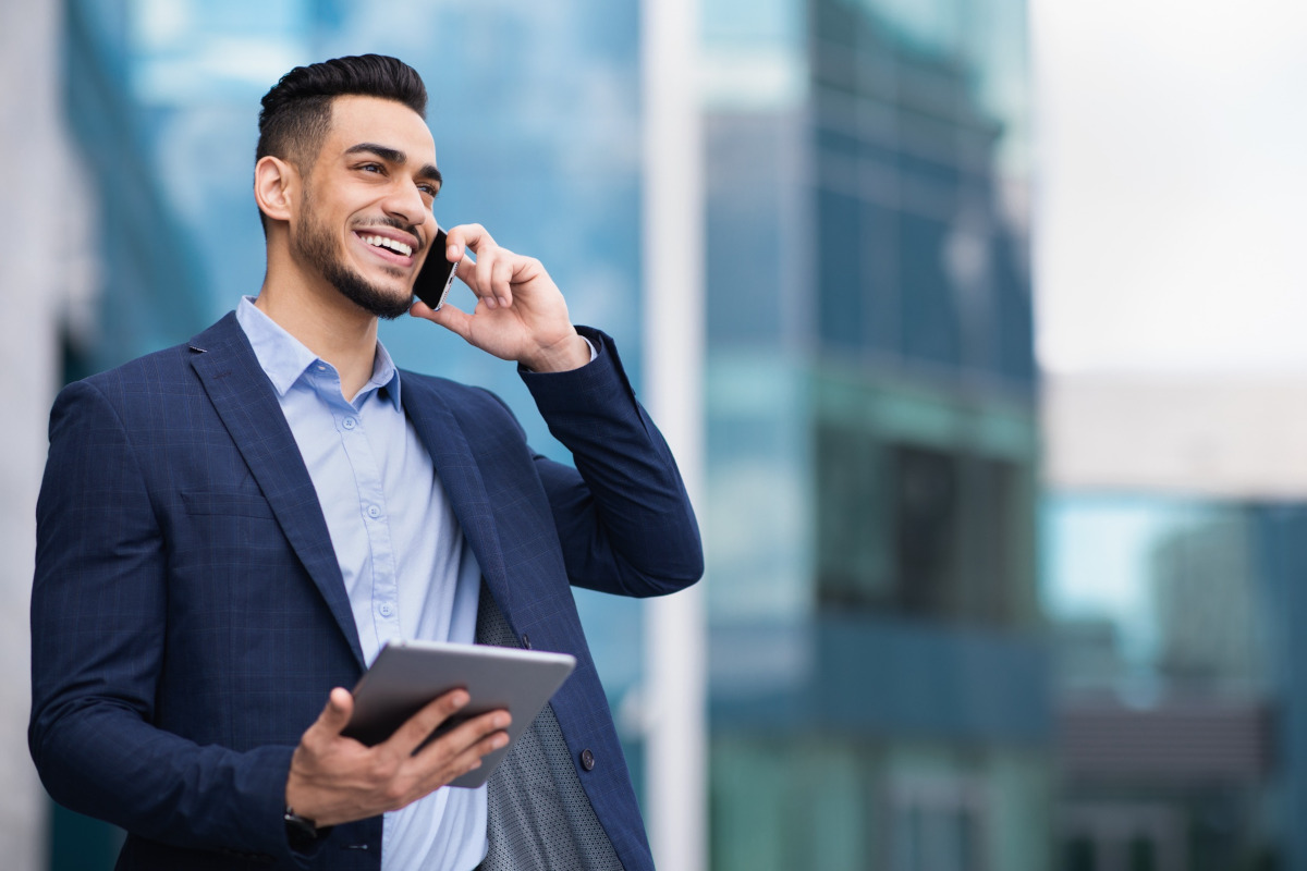 Smiling man holding a tablet and talking on phone