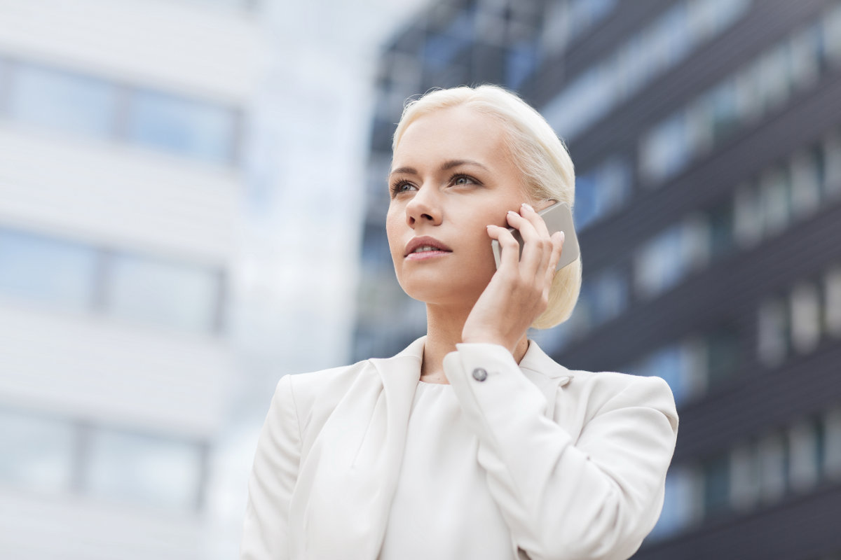 Woman in white talking on cell phone against blurred buildings