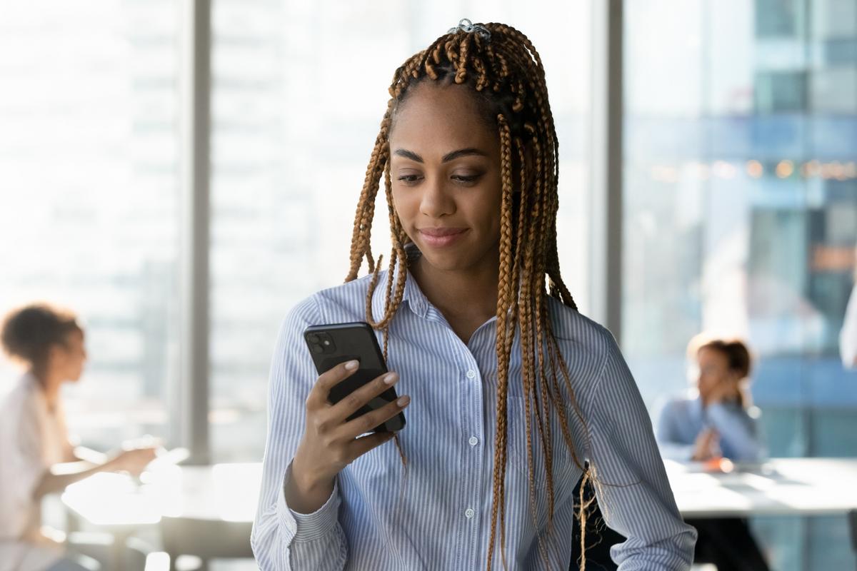 Woman in office holding a mobile phone and looking at the screen